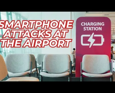 Empty airport seating area next to a red charging station with smartphones attacks warning text