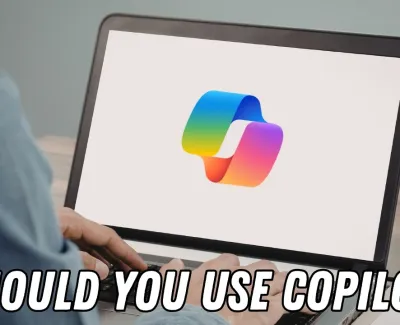 Person using laptop displaying colorful Microsoft Copilot logo with text Should You Use Copilot underneath.
