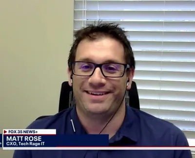 Man wearing glasses and earphones smiling during a virtual interview with Fox 35 News in a home office setting.