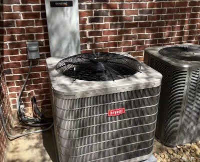 Outdoor Bryant air conditioning units installed on gravel next to a brick wall with electrical connections.