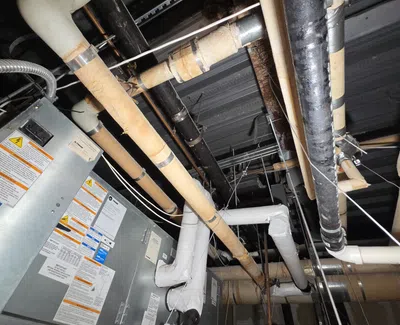Commercial HVAC system with insulated pipes and metal ductwork in an industrial ceiling space.