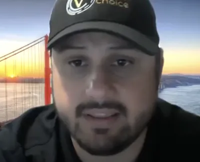 Man wearing a black cap with Golden Gate Bridge and sunset in the background during video call.