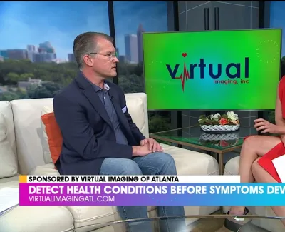 TV interview showing two people discussing health detection with Virtual Imaging logo on screen in a studio.