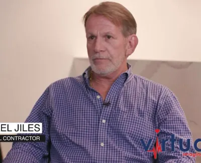 Michael Jiles, electrical contractor, seated indoors with plants in the background and Virtual Imaging logo visible.