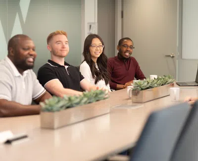 Diverse group of professionals seated around conference table in modern office during meeting.