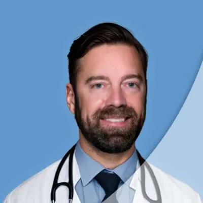 Smiling male doctor wearing a white coat and stethoscope against a blue background with a curved overlay.