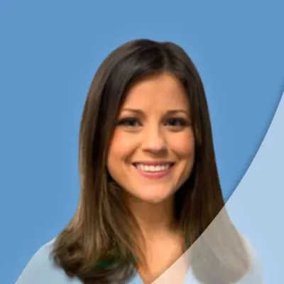 Smiling woman with brown hair wearing a light blue top against a blue background with curved graphic overlay.