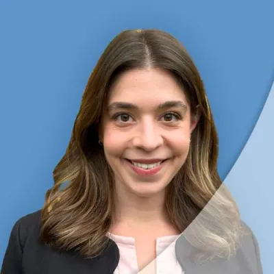 Young woman with shoulder-length brown hair smiling against a blue and gray background.