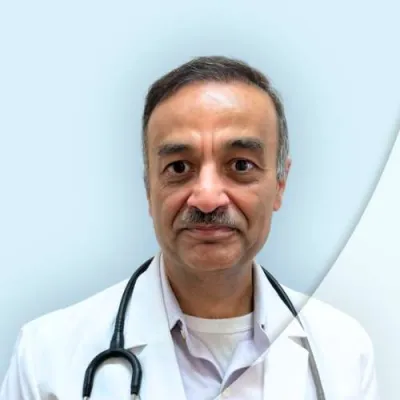 Portrait of a male doctor in white coat with stethoscope against a light blue background.