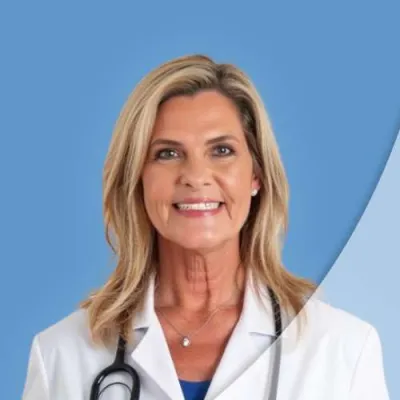 Smiling female doctor in white coat with stethoscope on blue background, professionally dressed and confident.