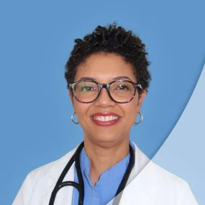 Smiling female doctor with short curly hair, glasses, and stethoscope wearing white coat on blue background.