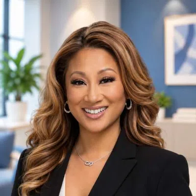 Smiling professional woman with wavy hair wearing black blazer in modern office setting