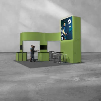 Green trade show booth with seating, counters, and a tall digital screen showing a tennis player hitting a backlit ball.
