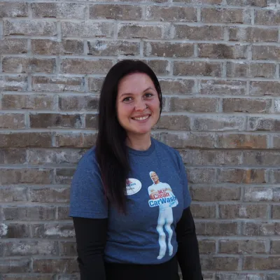 a woman smiling in front of a brick wall