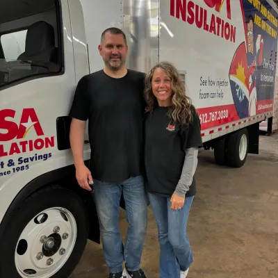 Two employees of USA Insulation stand in front of a service truck, promoting insulation services.