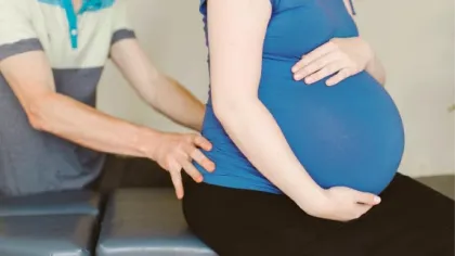 Pregnant woman receiving a back massage or chiropractic care during prenatal session indoors.