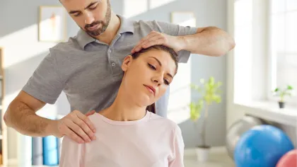 Chiropractor adjusting woman's neck in a bright therapy room with exercise balls and natural light