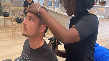 Man receiving a scalp treatment from a professional in a wellness center with shelves of products in the background