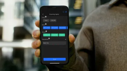 Person holding smartphone showing evening lights scheduling app with time, days, zones, and save button.