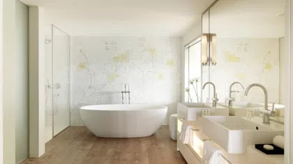 Modern bathroom with freestanding tub, double sinks, large mirror, wood floor, and floral wall design.