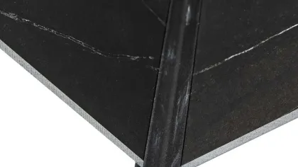 Close-up of black textured floor tiles joined with a dark metal corner trim piece