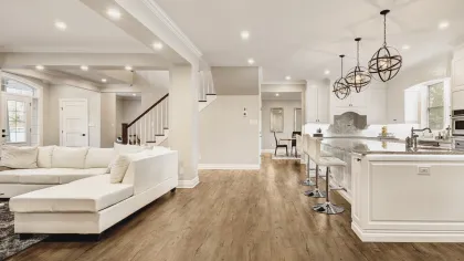 Modern open-concept living room and kitchen with white cabinetry, wood flooring, and contemporary light fixtures