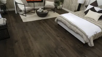 Modern bedroom with dark wood flooring, neutral bedding, cozy seating area, and electric wall fireplace.