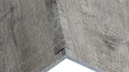 Close-up of two wood-patterned laminate flooring panels connected with a click-lock system.