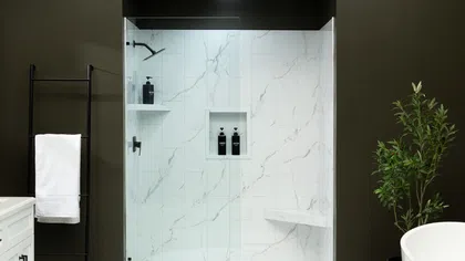 Modern bathroom with dark walls, white freestanding tub, walk-in shower, double vanity, and round white rug