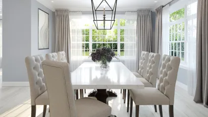 Bright dining room with a large white table, six beige tufted chairs, patterned ceiling, and large windows with curtains.