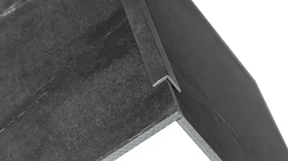 Close-up of a black cardboard or paperboard corner with a white interior and a folded tab edge.