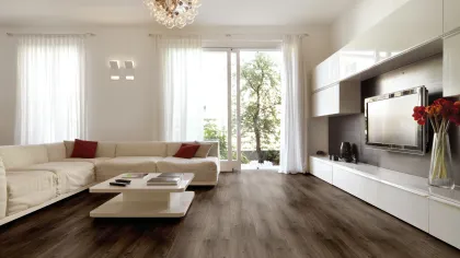 Modern living room with white sectional sofa, dark wood flooring, large windows, and sleek white cabinetry.