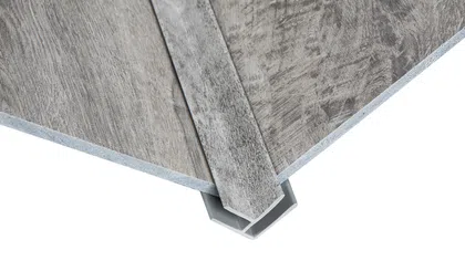 Close-up of gray wood-look vinyl flooring panels with an interlocking edge system on white background
