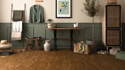 Cozy room with cork flooring, green paneled walls, wooden furniture, potted plant, and woven storage basket.