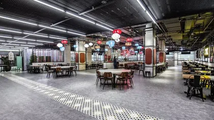 Spacious modern dining area with diverse seating, colorful hanging lanterns, and industrial ceiling design.