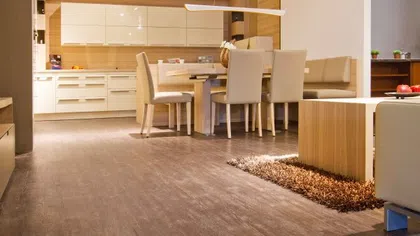 Modern dining area with beige chairs, wooden table, and white kitchen cabinets in bright open space
