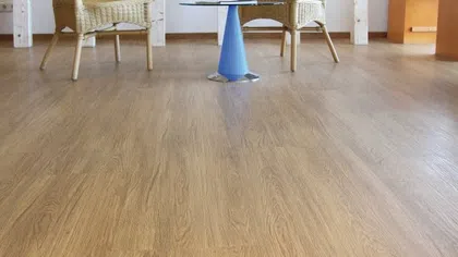 Modern room with light wood flooring, wicker chairs, and a small glass-top blue table in the center.