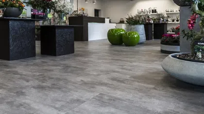 Modern flower shop interior with gray flooring, black display pedestals, and green decorative elements.