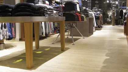Clothing store interior with neatly folded sweaters and shirts on wooden tables and shelves.