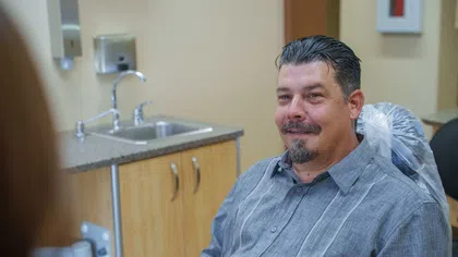 Smiling man with goatee sitting in dental chair in a modern clinic setting