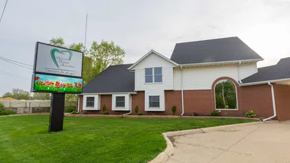 Exterior view of Ortreven Dental Associates building with green lawn and large signage on a cloudy day