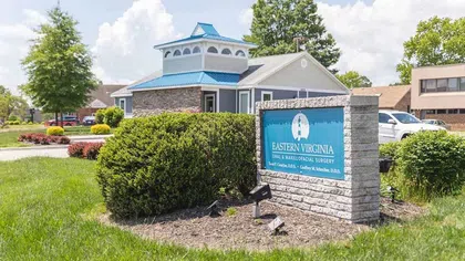 Eastern Virginia Oral & Maxillofacial Surgery office building with blue roof and signage on sunny day