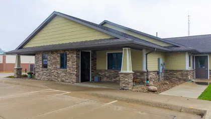 Modern single-story building with stone and yellow siding exterior and covered entrance on cloudy day