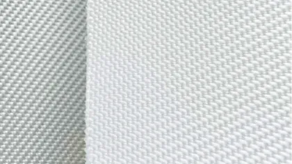 Close-up of white woven fabric with textured surface and fine mesh pattern under bright lighting.
