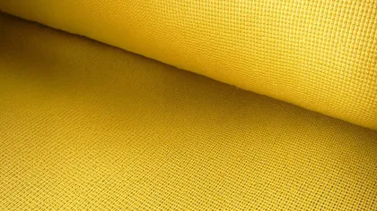 Close-up of bright yellow woven fabric with textured grid pattern in a rolled piece of cloth.
