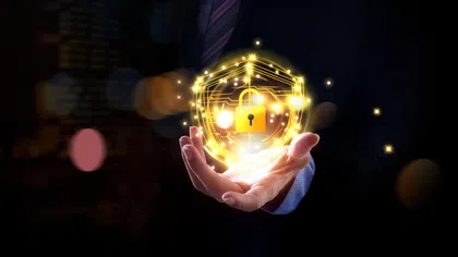 Businessman holding glowing golden shield with digital lock symbol representing cybersecurity and data protection.