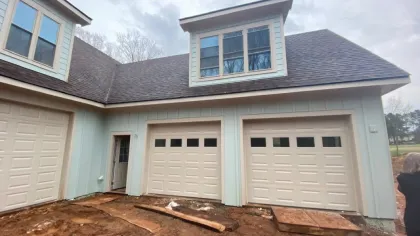 a house with garages and a dirt yard