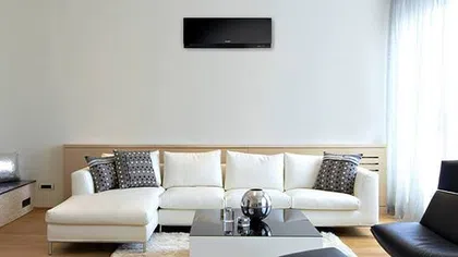 Modern living room with a stylish white sofa, decorative pillows, and sleek furniture, featuring a minimalist design.