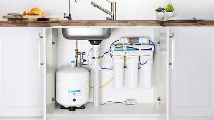 Under-sink kitchen water filtration system with modern faucet and organized plumbing.