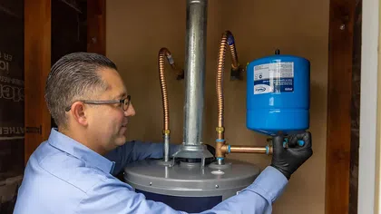 Technician installing a blue water tank on a modern home water heater system.